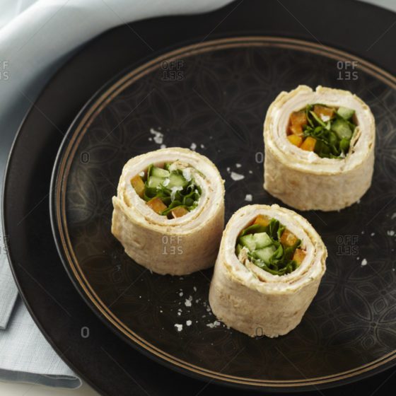 Three rolls of food on a black plate.