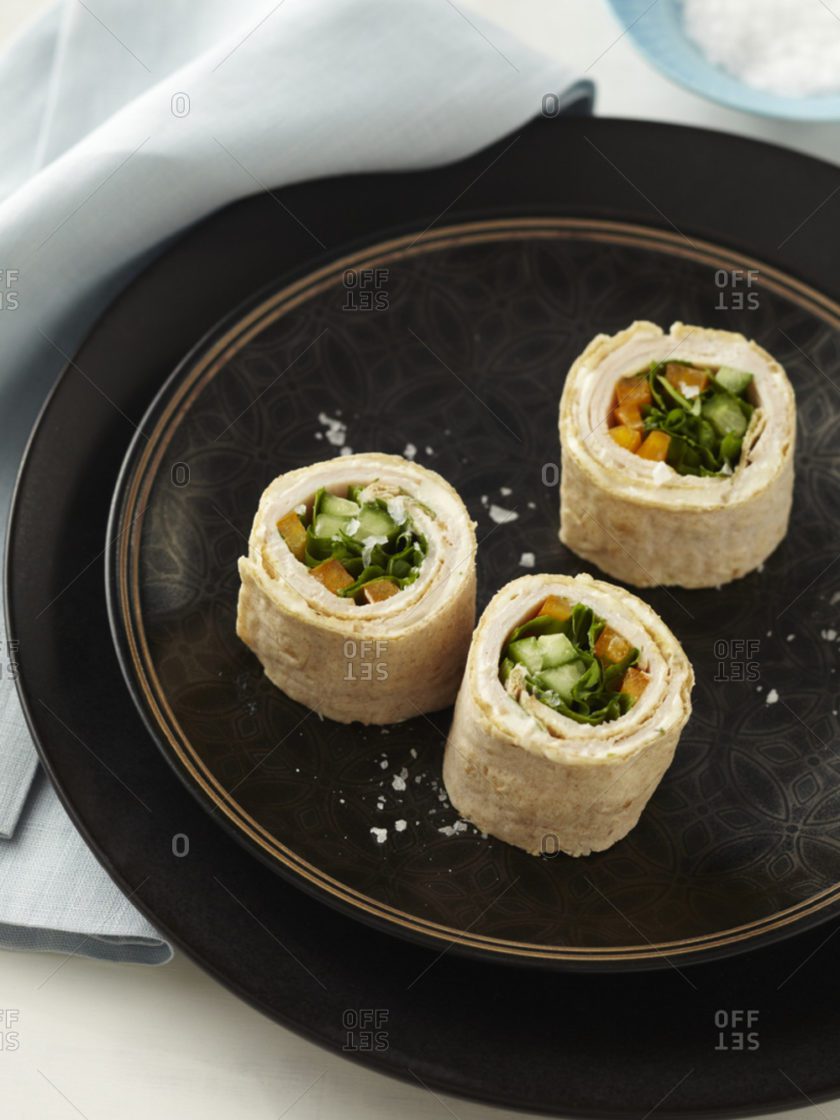 Three rolls of food on a black plate.