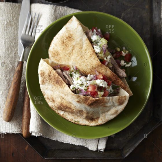 A green plate with two pieces of tortilla and salad.