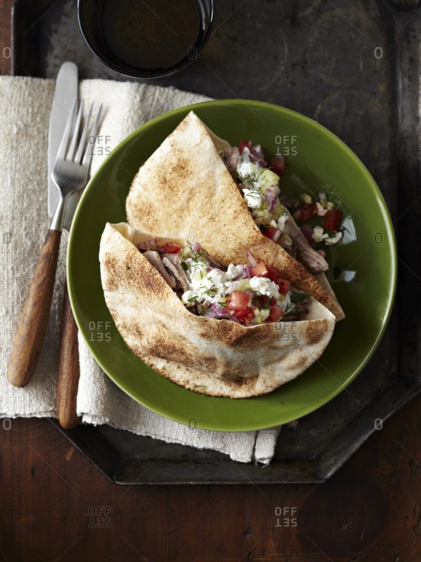 A green plate with two pieces of tortilla and salad.