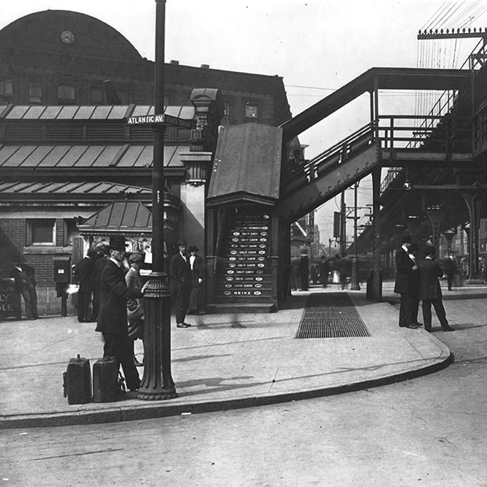 A black and white photo of people waiting at the train station.