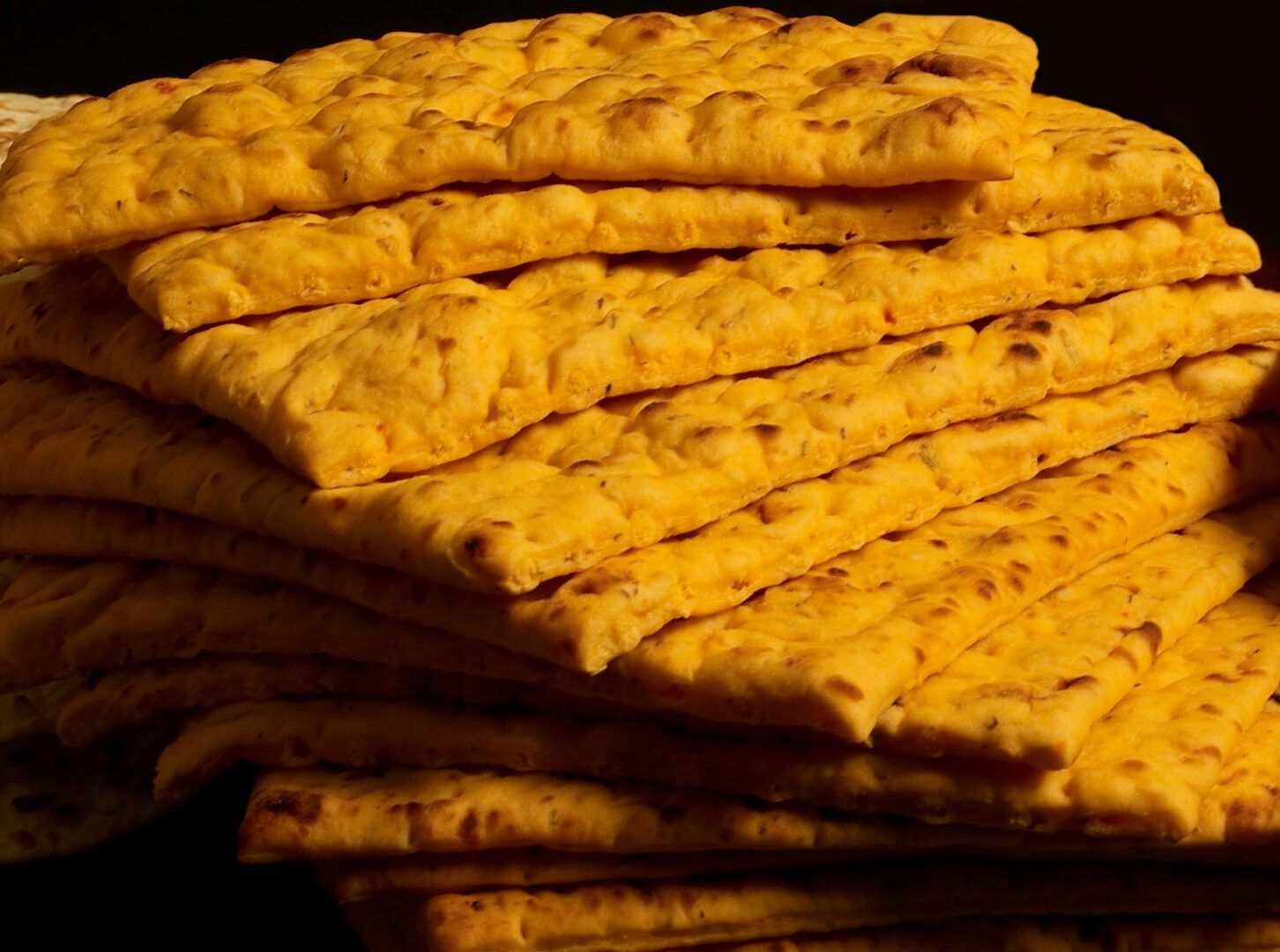 A stack of crackers with yellow colored crust.